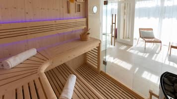Un sauna avec des bancs en bois, une porte en verre donnant sur l’extérieur et une vue sur l’espace extérieur.