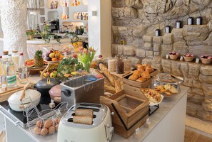 A buffet setup with various food items, including bread, pastries, and fruits.