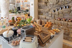 Una mesa de buffet con diferentes opciones de comida, incluyendo pan, bollería y frutas.