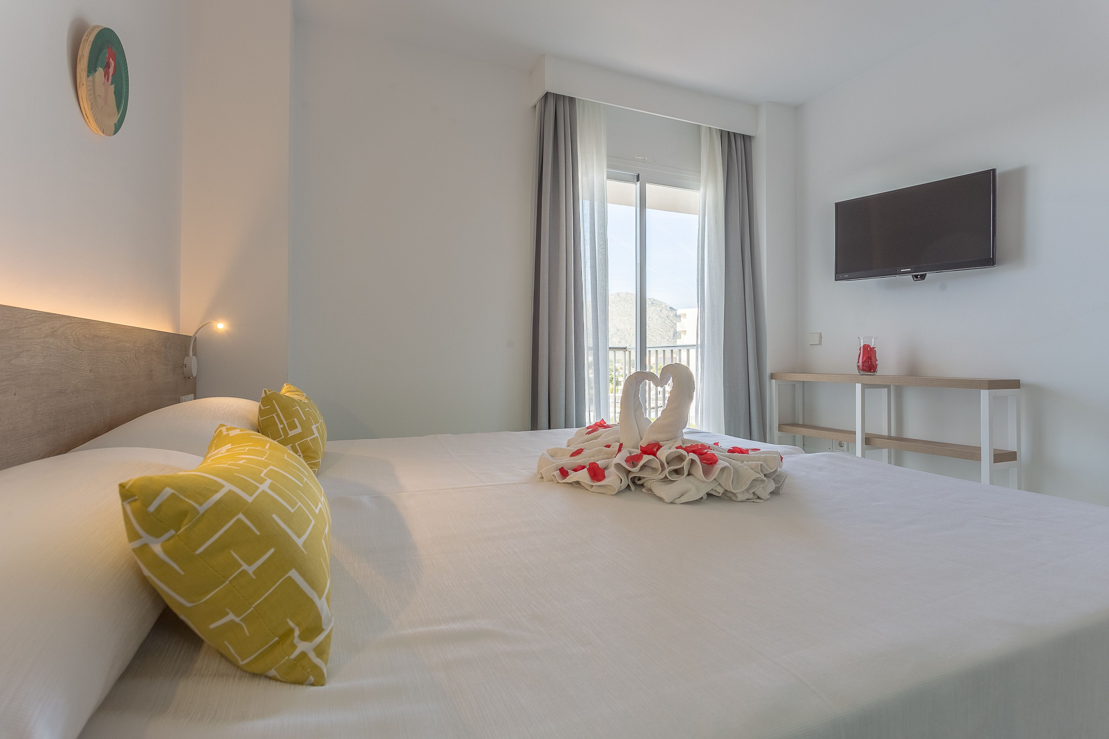 Habitació d'hotel amb llit, televisió i finestra amb cortines.