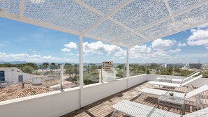 Terraza en la azotea con mobiliario blanco y vista panorámica de la ciudad.