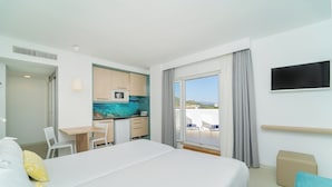 Una habitación de hotel con cama, escritorio, kitchenette y balcón con vistas.