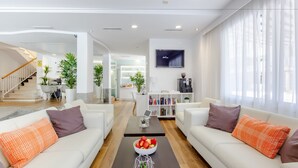 Una sala de estar moderna con un conjunto de sofá, una mesa de centro con fruta y un televisor montado en la pared.