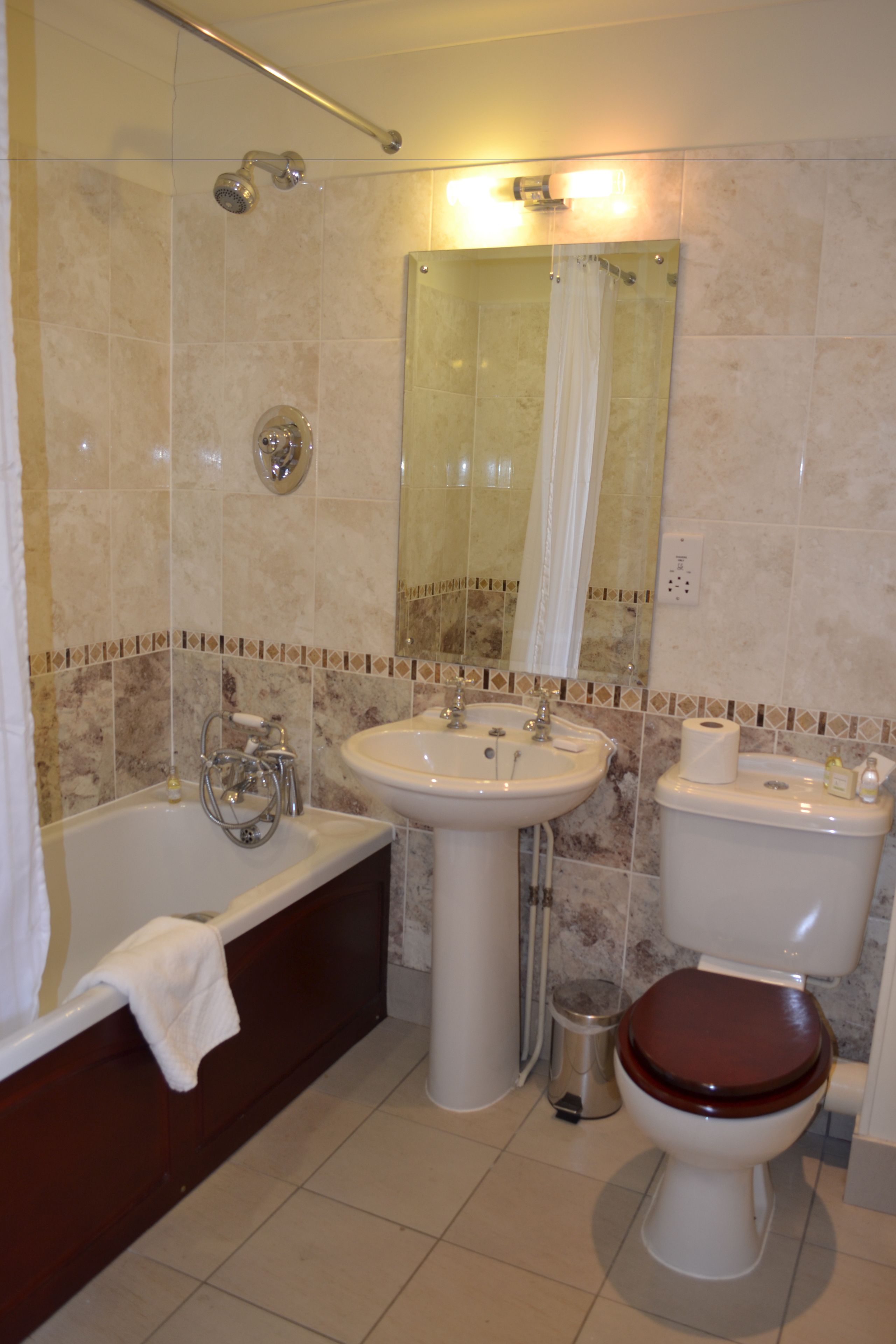 A bathroom with a bathtub, sink, toilet, and a showerhead.