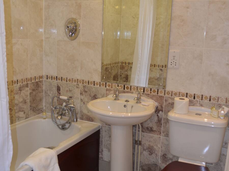 A bathroom with a bathtub, sink, toilet, and a showerhead.