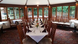A dining area with a long table set for a meal, surrounded by wooden chairs.