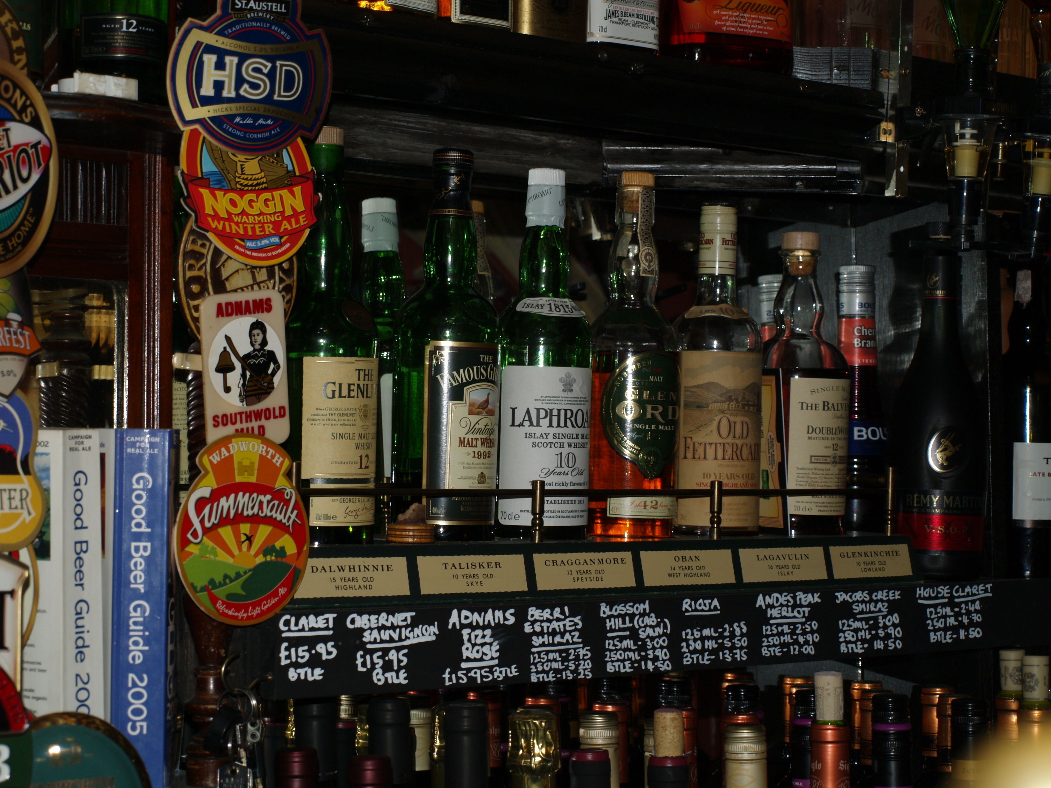 A bar with various bottles of alcohol, including whisky and wine, and a selection of beer guides.
