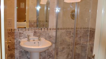 A bathroom with a sink, mirror, and glass shower enclosure.