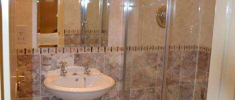 A bathroom with a sink, mirror, and glass shower enclosure.
