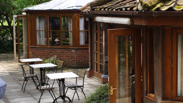 A patio with tables and chairs, a brick wall, and a wooden door.