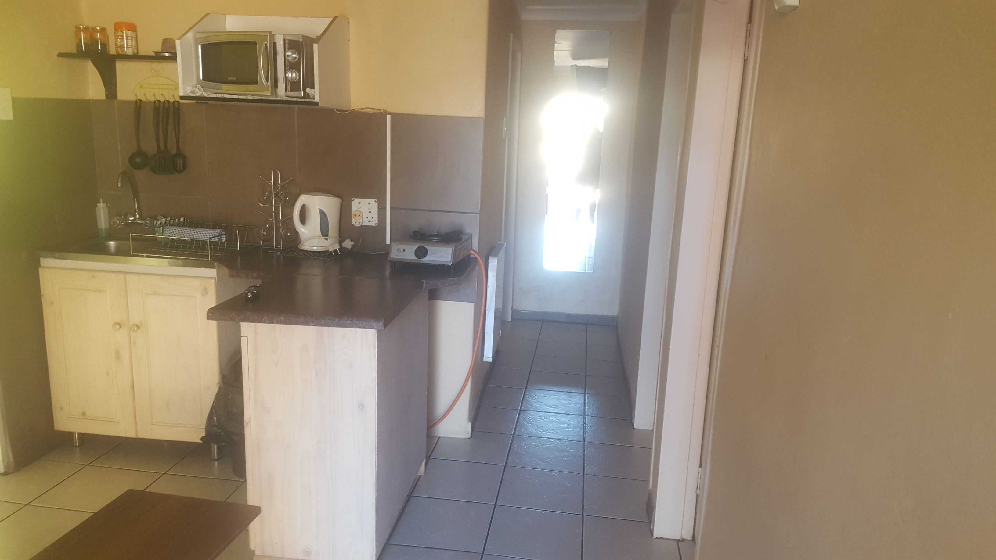 A kitchen with a microwave, kettle, and a small island with a sink.