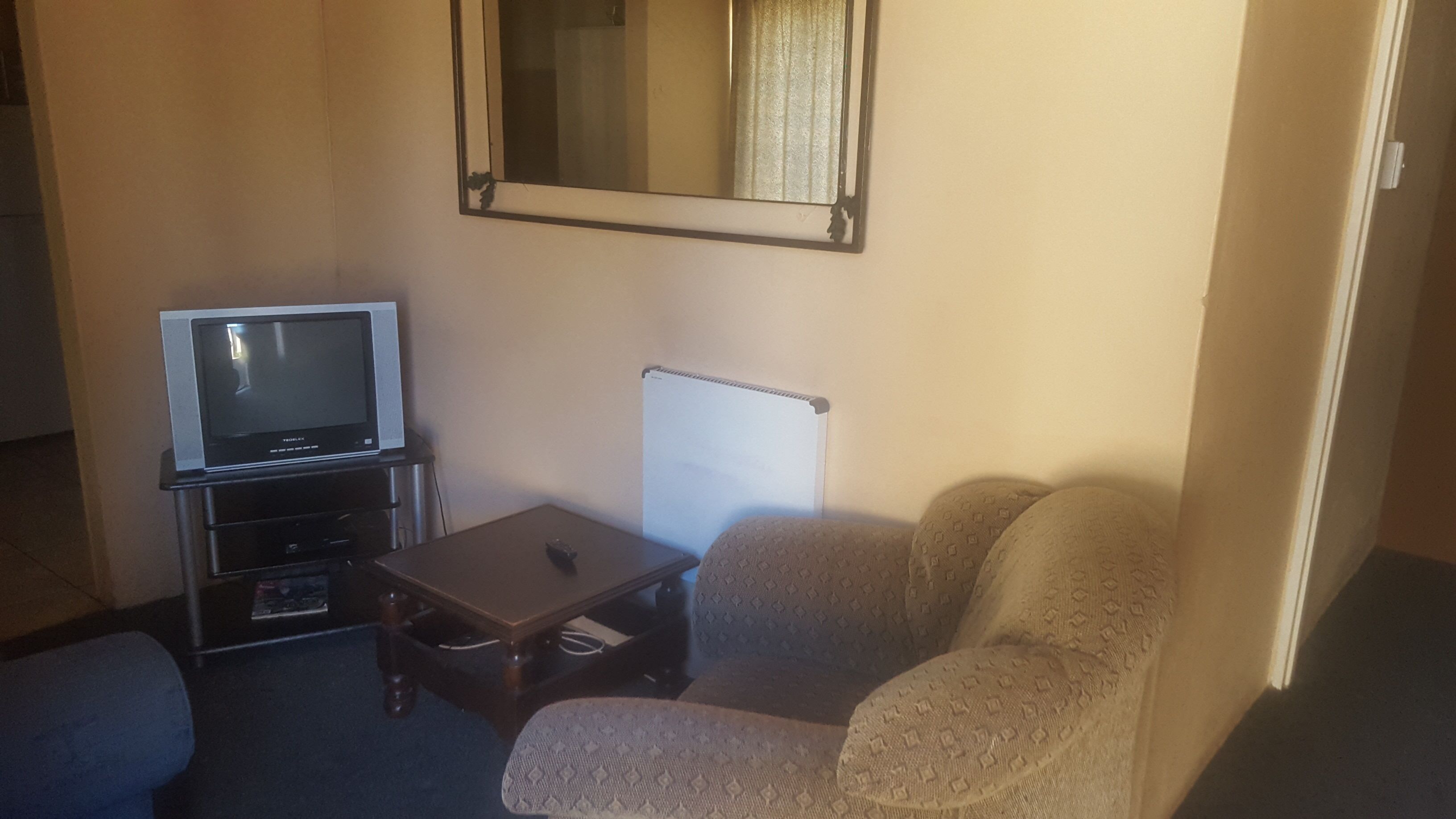 Una sala pequeña con televisión, una mesa y un sofá.