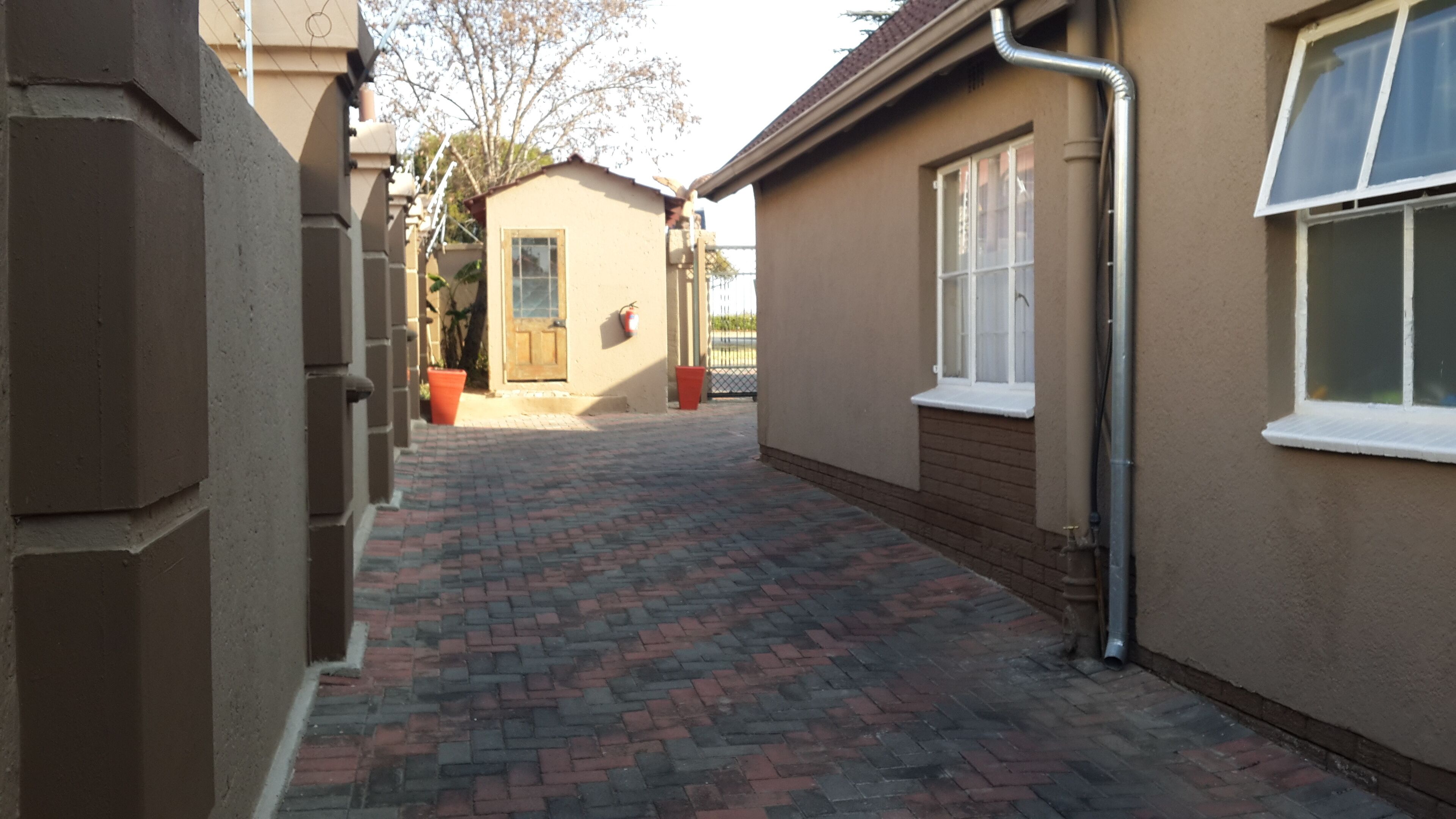 Un chemin pavé mène à un bâtiment doté d’une fenêtre et d’une porte.