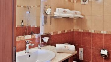 A hotel bathroom with a sink, mirror, towel rack, and a hand dryer.