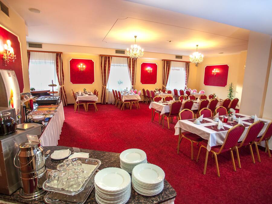 A banquet hall with tables set for dining, a buffet area, and a bar.