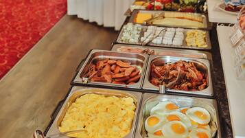 Een ontbijtbuffet met diverse gerechtjes, zoals eieren, worst en groenten.