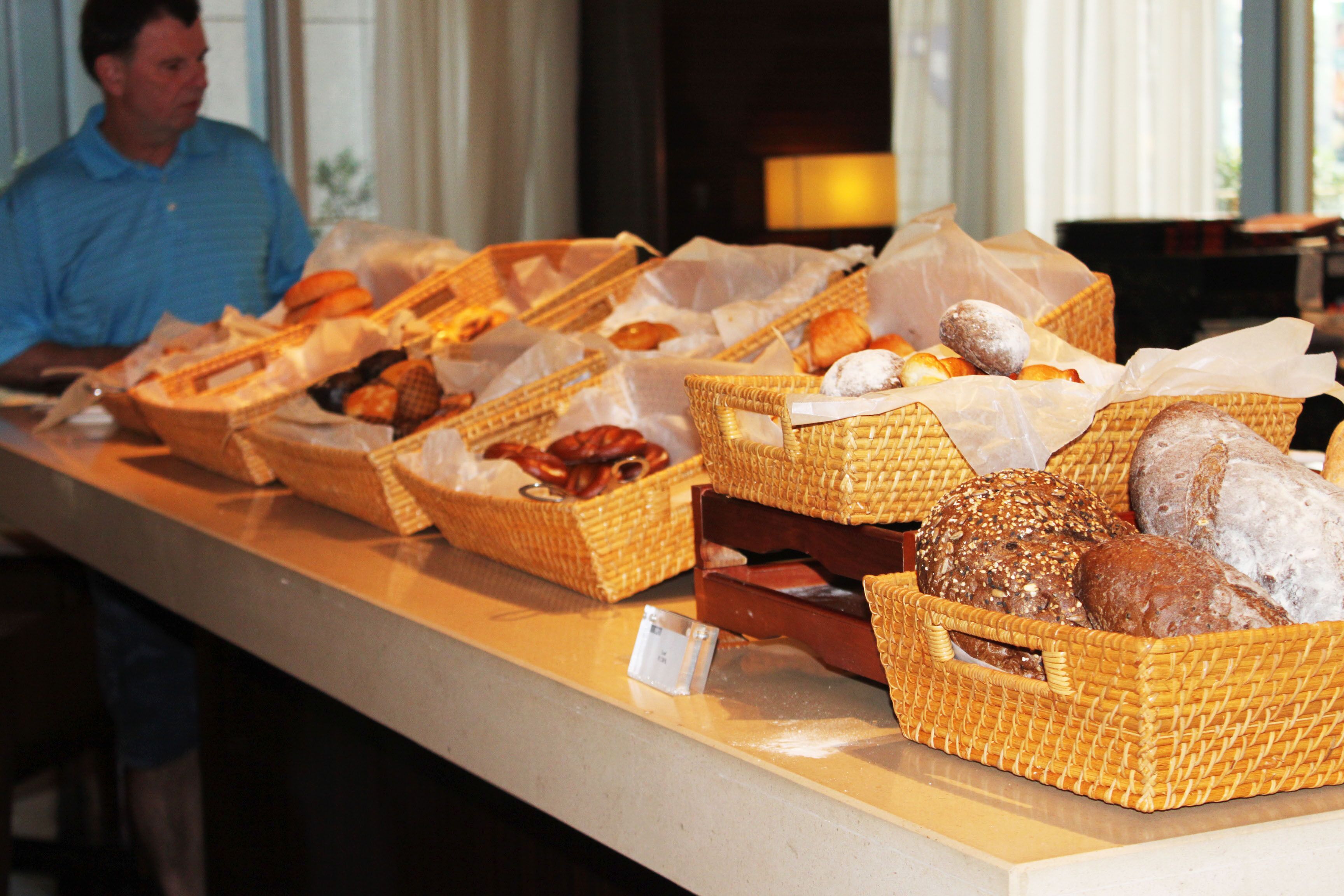 Una mesa de buffet con panes y pasteles diversos en cestas de mimbre.