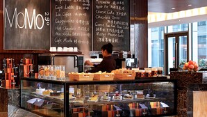 Una cafetería MoMo con un panel de menú que muestra diferentes opciones de café y postres.