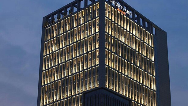 Un edificio de hotel alto con una cuadrícula de ventanas y un cartel que dice "Courtyard by Marriott".
