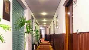 A hotel hallway with a wooden floor, potted plants, and a sign indicating room number 101. - Hotel One The Mall Lahore (Lahore)
