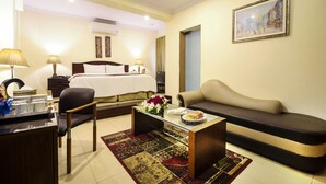 A hotel room with a bed, a sofa, a desk with a lamp, and a painting on the wall. - Hotel One The Mall Lahore (Lahore)