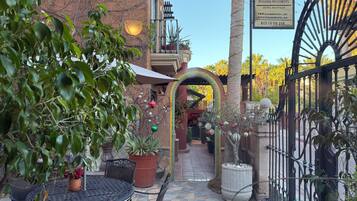 Un patio con una mesa redonda y sillas, una planta en maceta y un letrero para el Hotel Boutique Posada del Cortes.