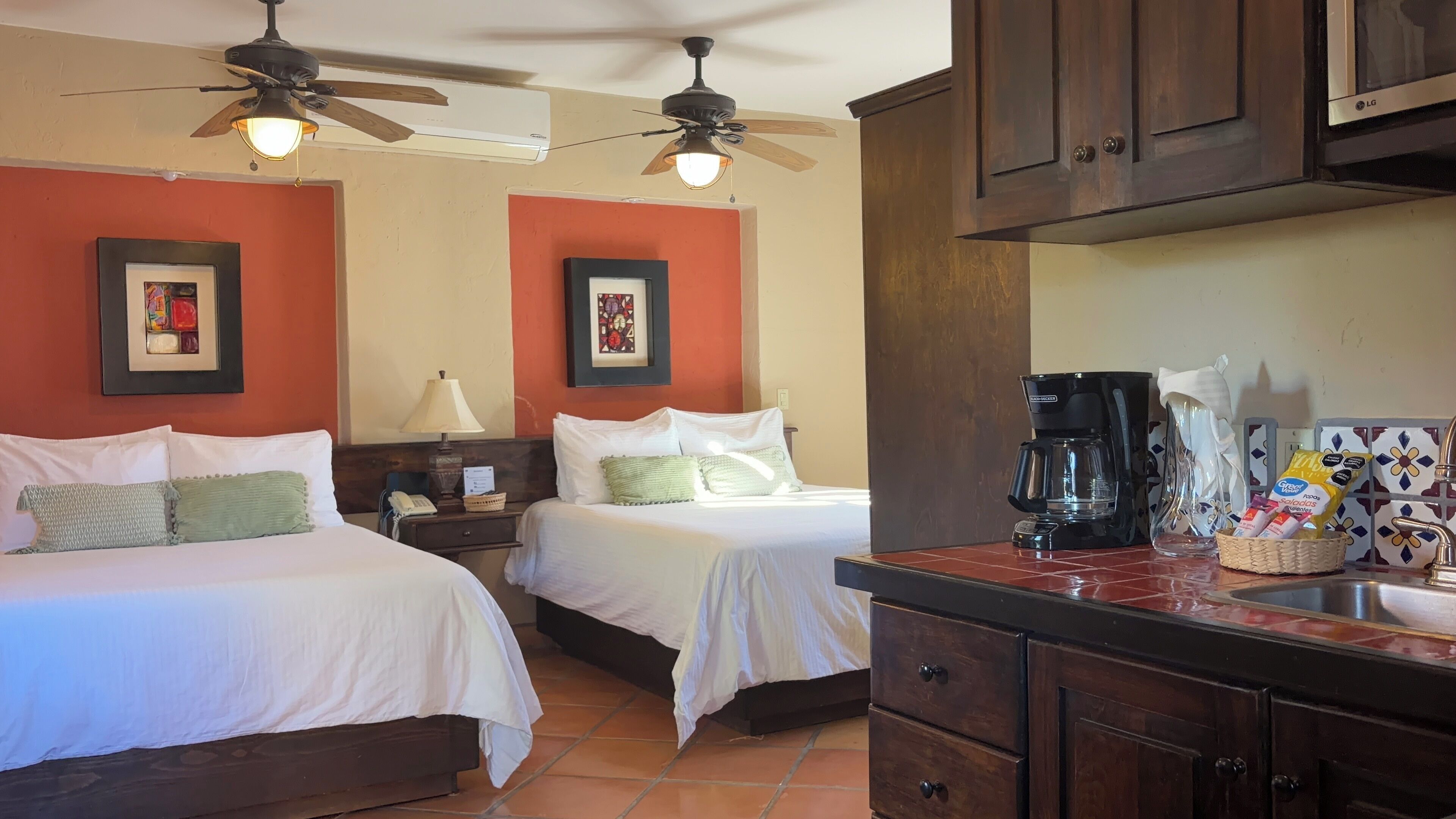 Habitación de hotel con dos camas, cafetera y barra de desayuno.