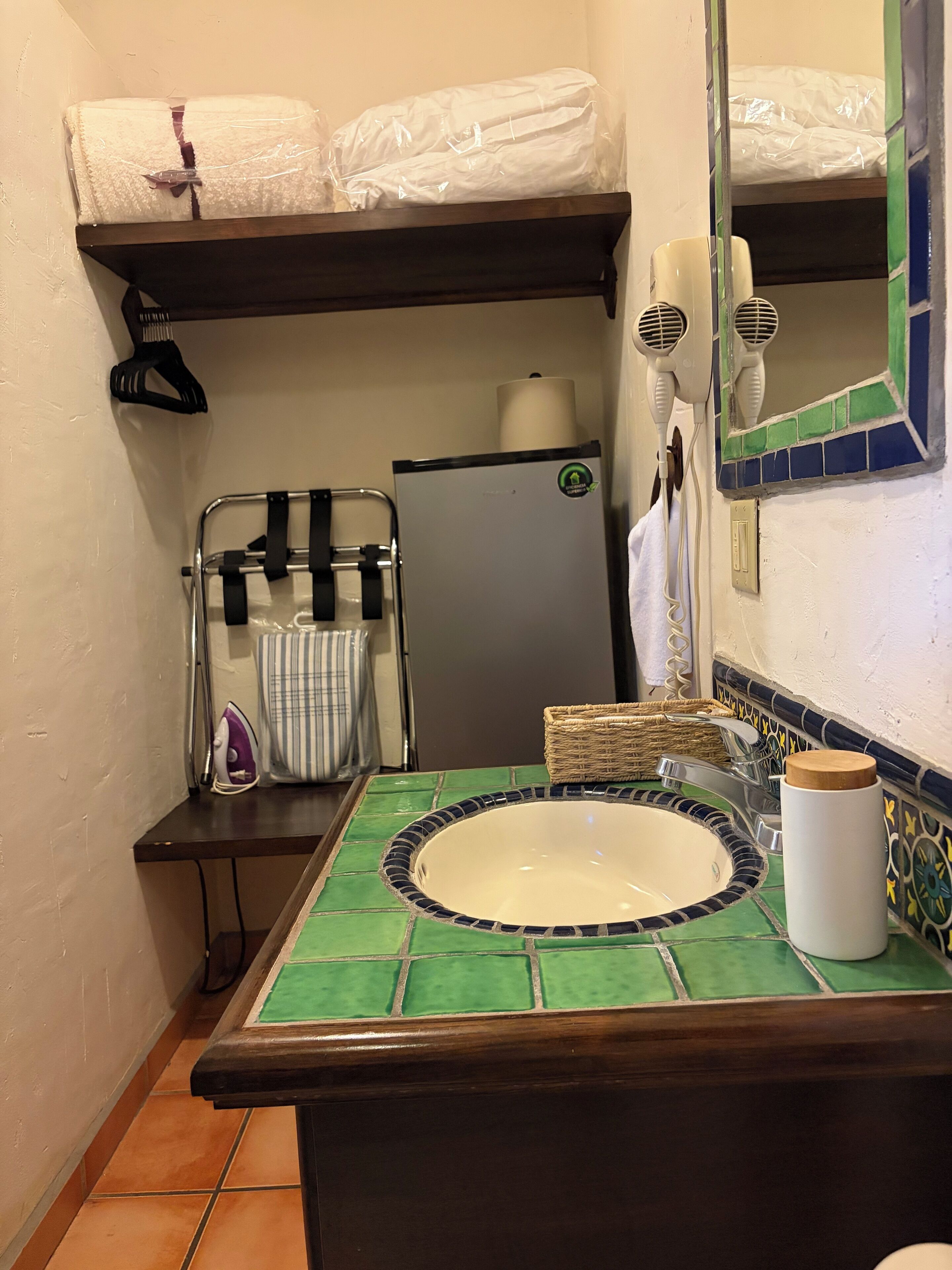 A bathroom with a sink, a towel rack, a hairdryer, and a small refrigerator.