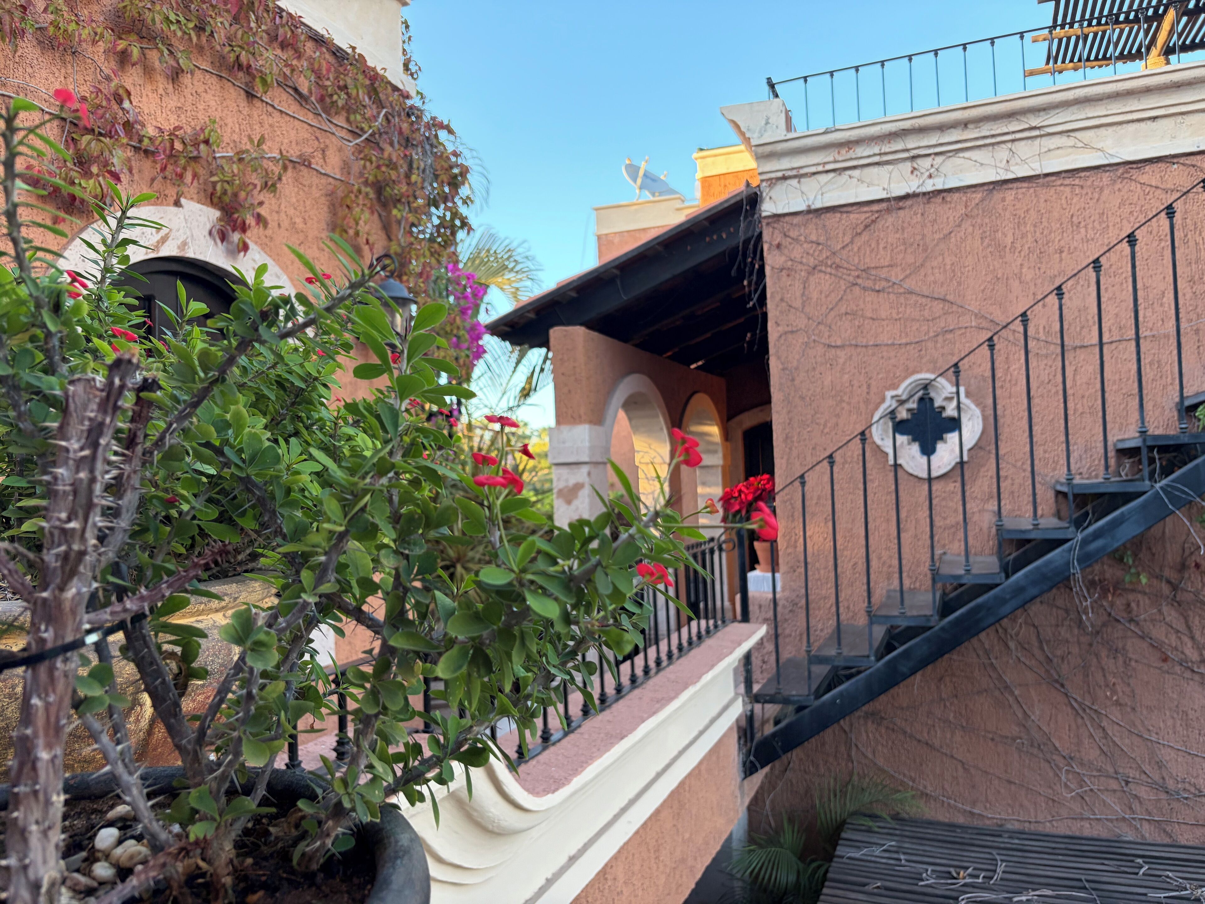 A staircase with a wrought iron railing leading to a building with a textured wall and a decorative emblem.