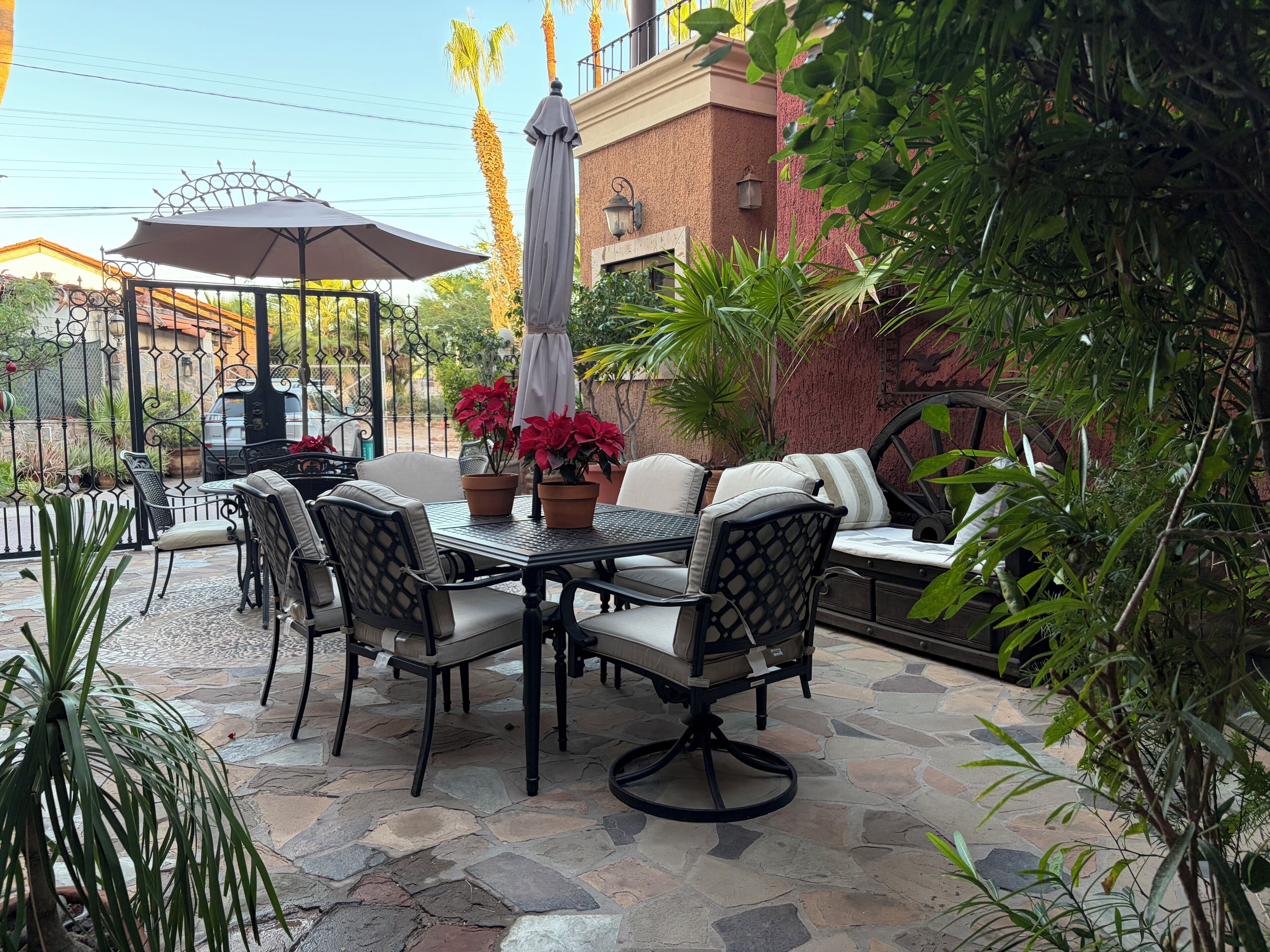 An outdoor patio with a table and chairs, surrounded by potted plants and a brick wall.