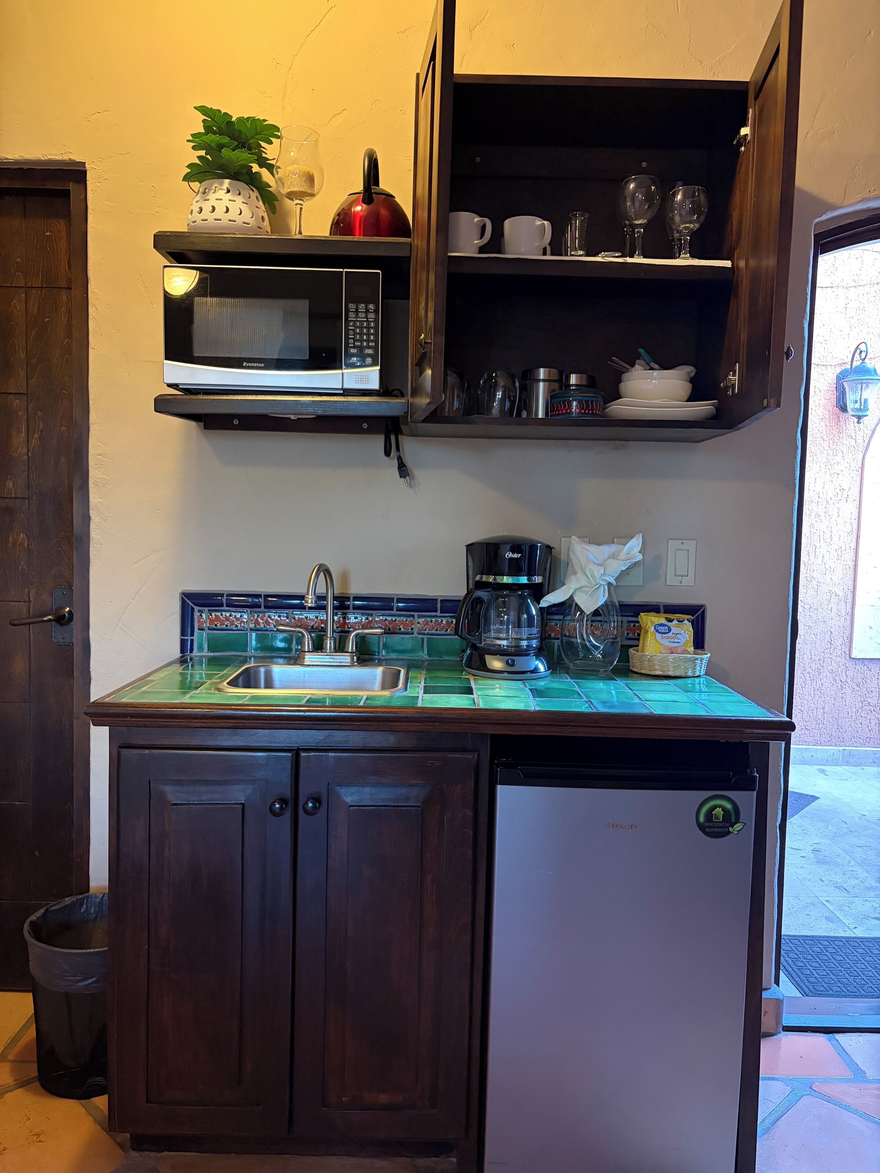 A compact kitchen with a microwave, coffee maker, and a sink.