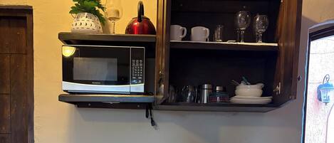 A compact kitchen with a microwave, coffee maker, and a sink.