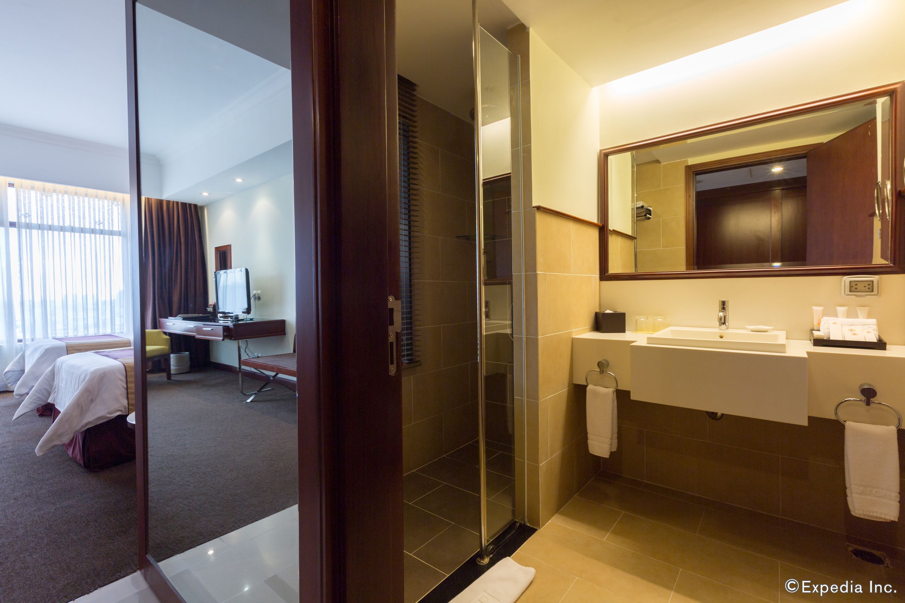 Ein Hotelbad mit Duschkabine aus Glas, zwei Waschbecken und einem großen Spiegel.
