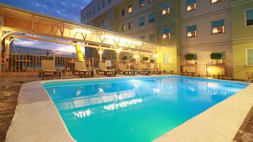 Een buitenzwembad, ligstoelen bij het zwembad