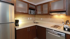 Eine moderne Küche mit Edelstahlgeräten, Holzschränken und einer gefliesten Spritzschutzwand.