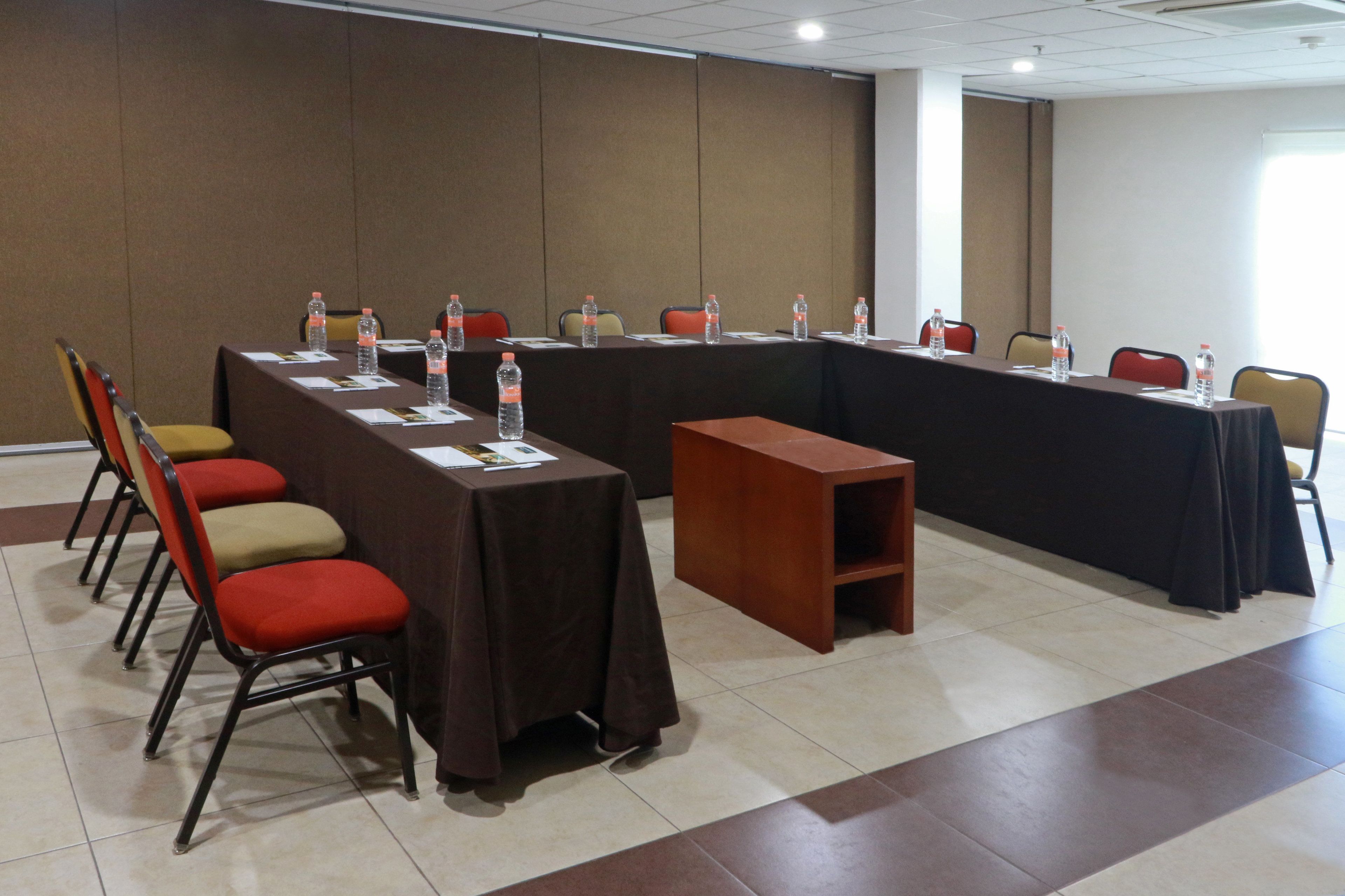 Una sala conferenze con un lungo tavolo, sedie e bottiglie d'acqua.