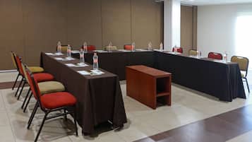 Una sala conferenze con un lungo tavolo, sedie e bottiglie d'acqua.