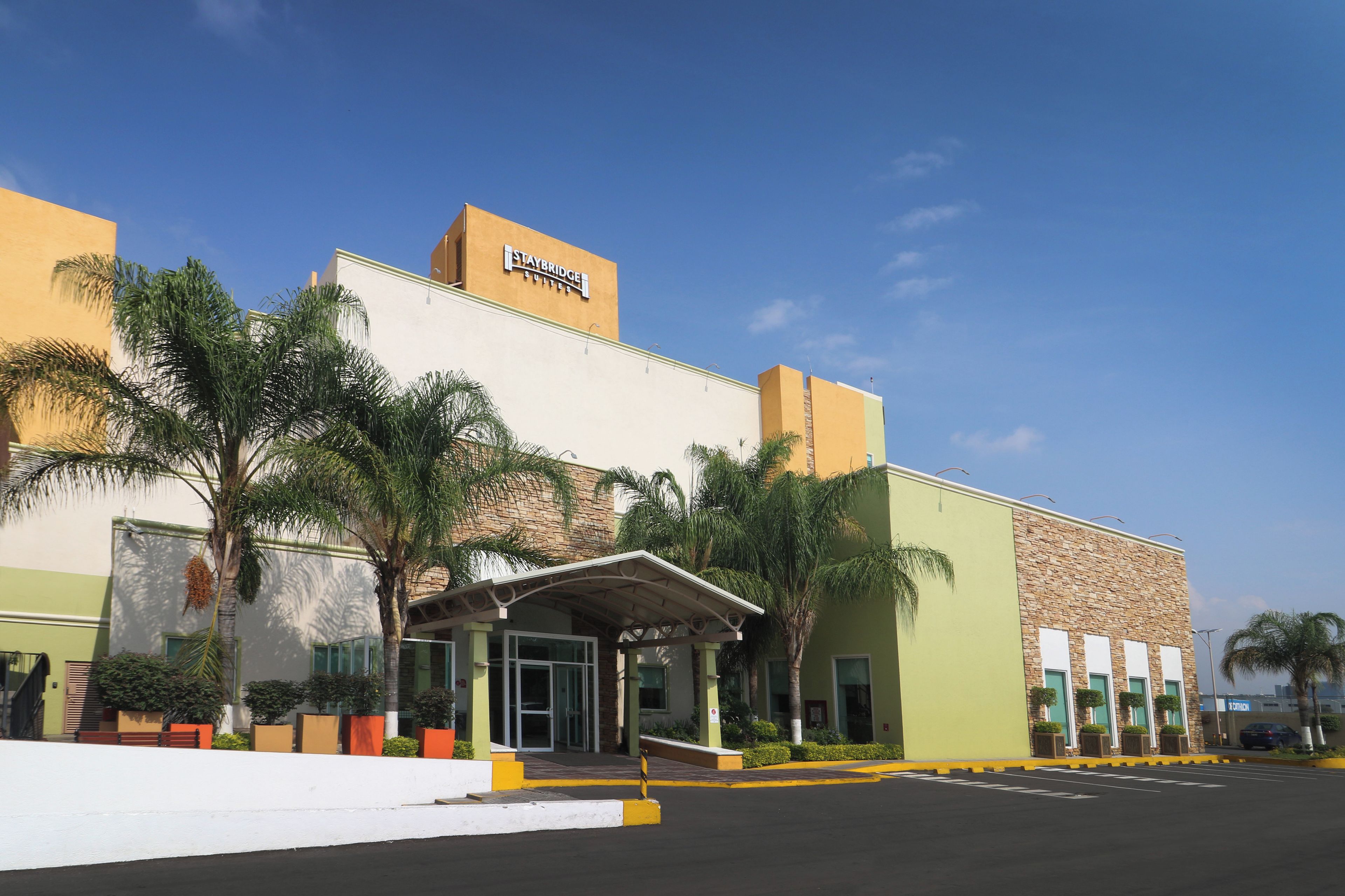 Un hotel Staybridge Suites con diseño moderno, que cuenta con una entrada destacada y un estacionamiento.