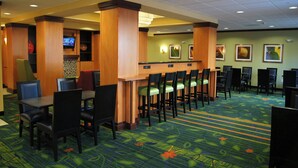 Un vestíbulo de hotel con mostrador de recepción, varios taburetes de bar y suelo alfombrado.