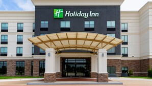 A Holiday Inn hotel entrance with a modern design, featuring a covered entryway and multiple windows.