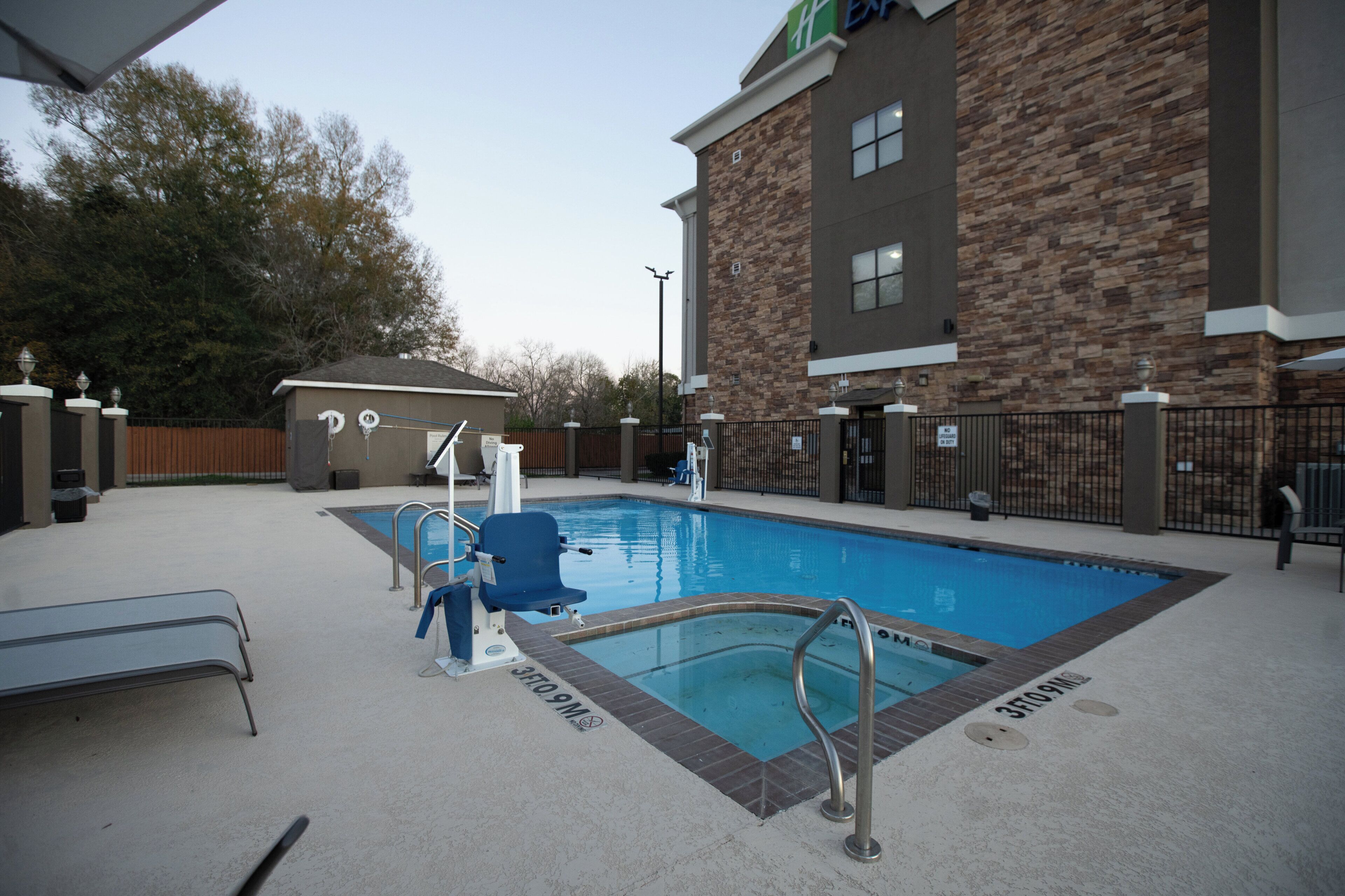 A swimming pool with a lifeguard stand, a changing room, and a building with a stone facade.