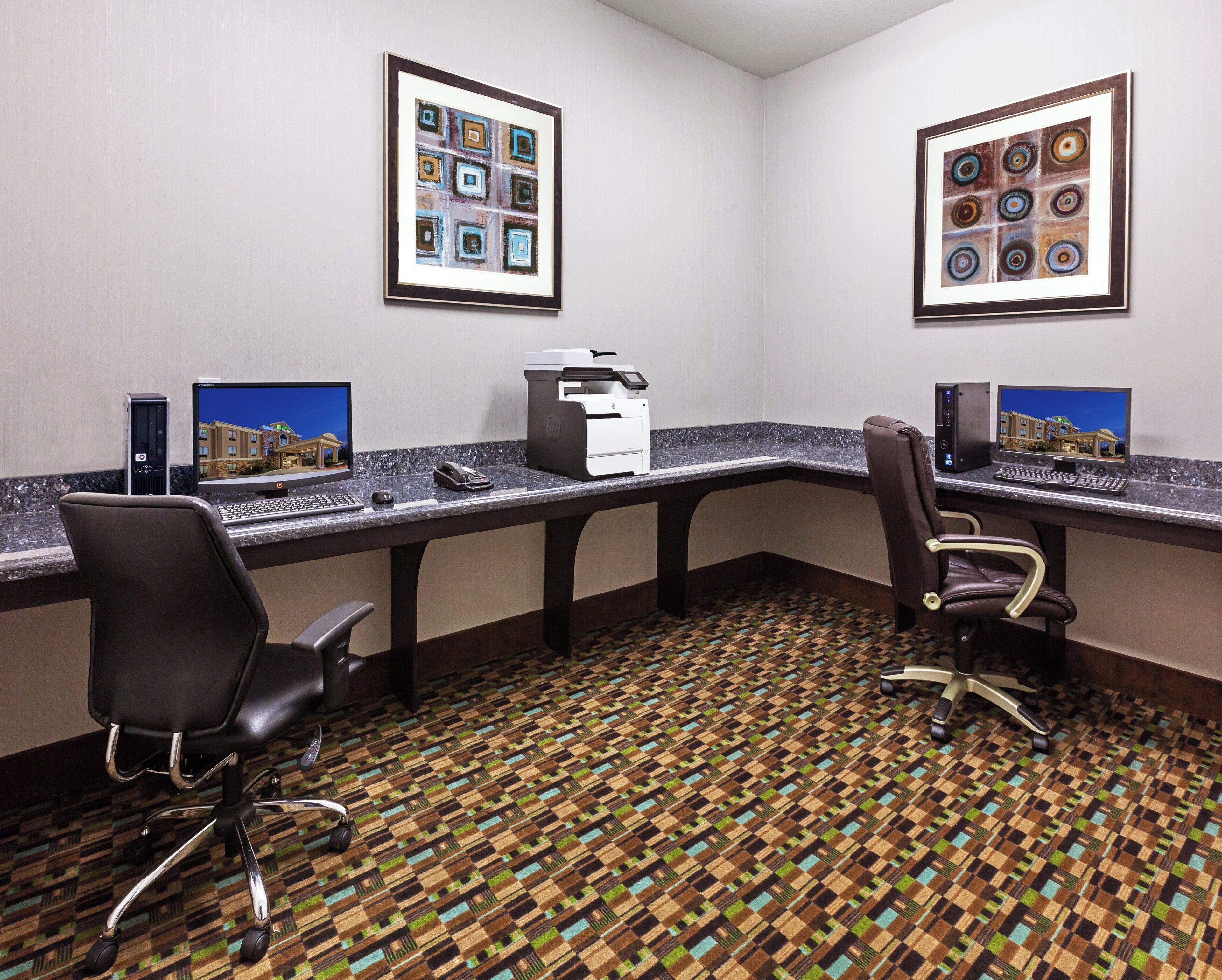 A hotel office with two desks, chairs, a printer, and framed artwork on the walls.