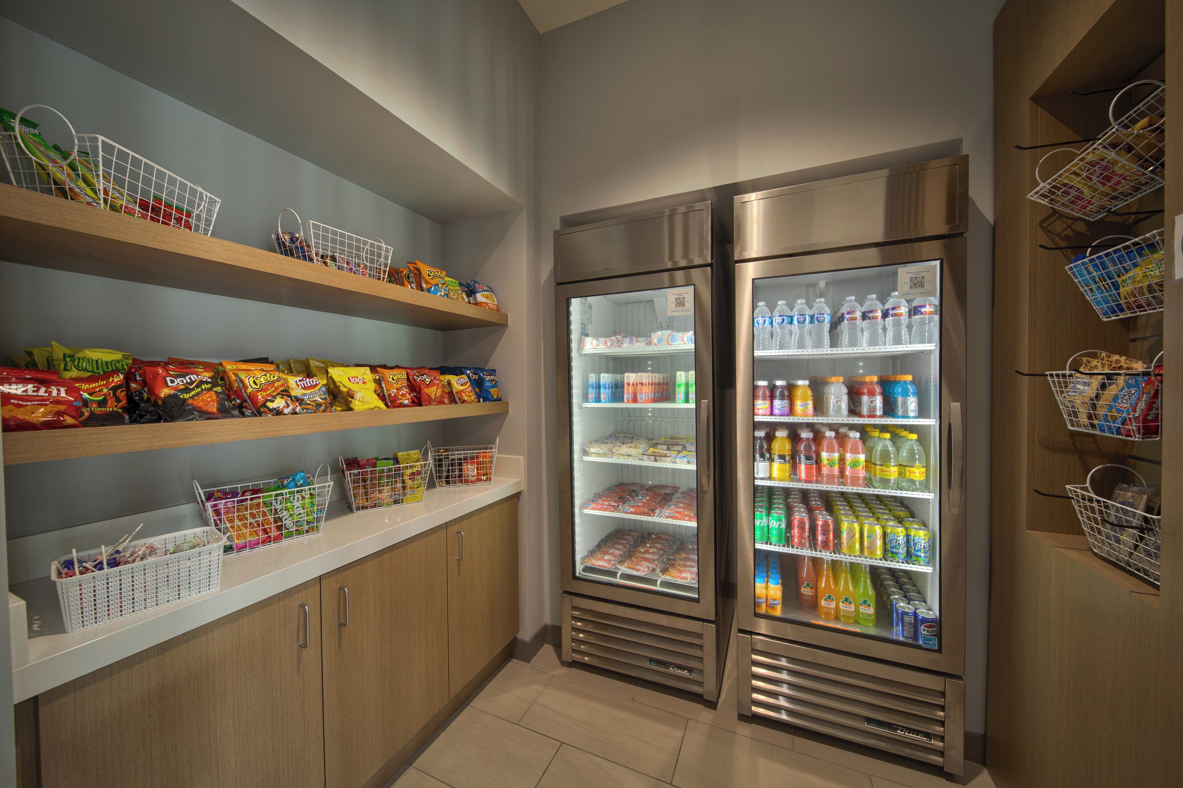 A self-service snack and beverage area with refrigerated sections and shelves stocked with various snacks and drinks.