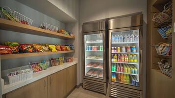 A self-service snack and beverage area with refrigerated sections and shelves stocked with various snacks and drinks.