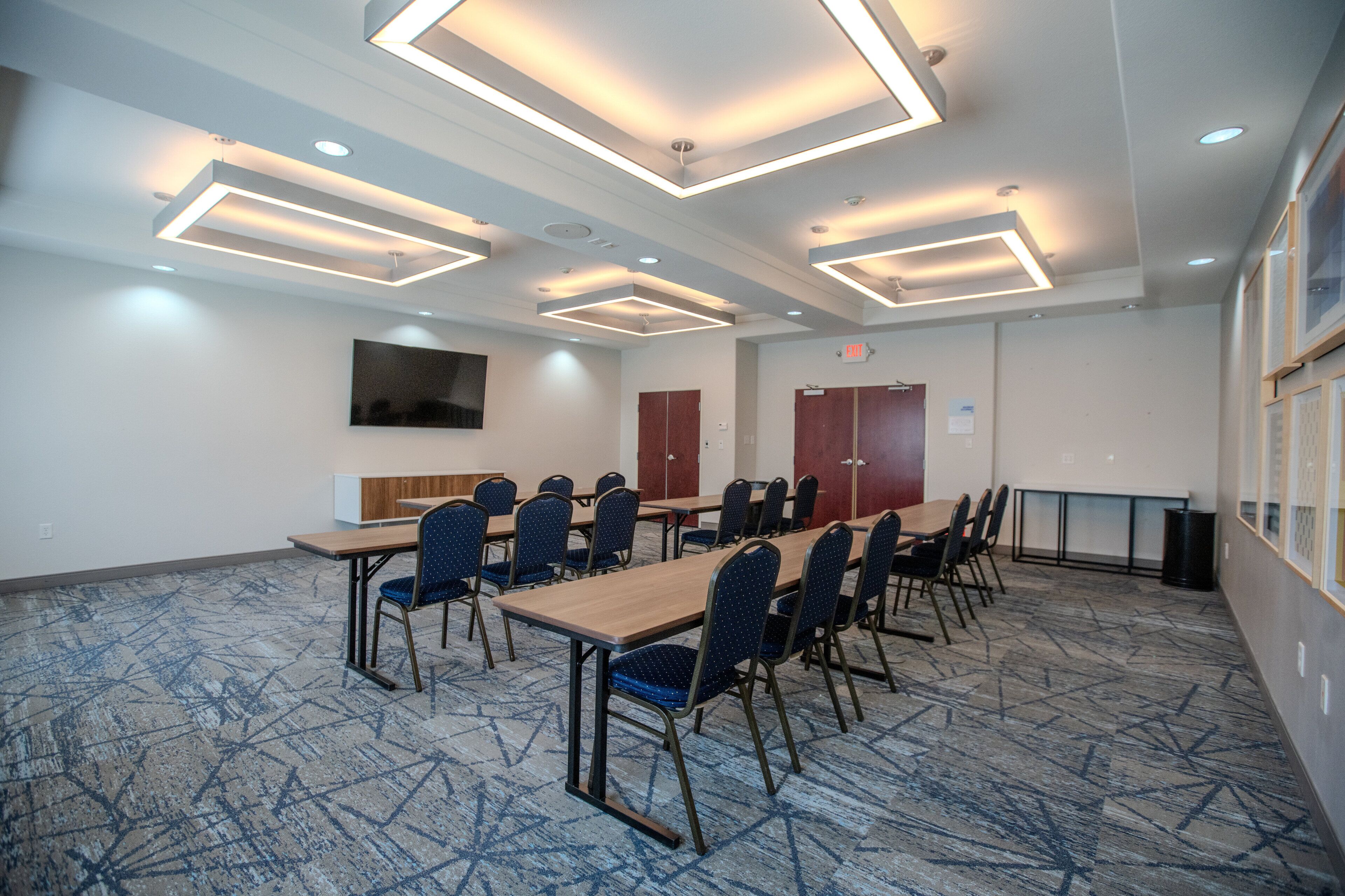 A conference room with a long table, chairs, and modern lighting fixtures.