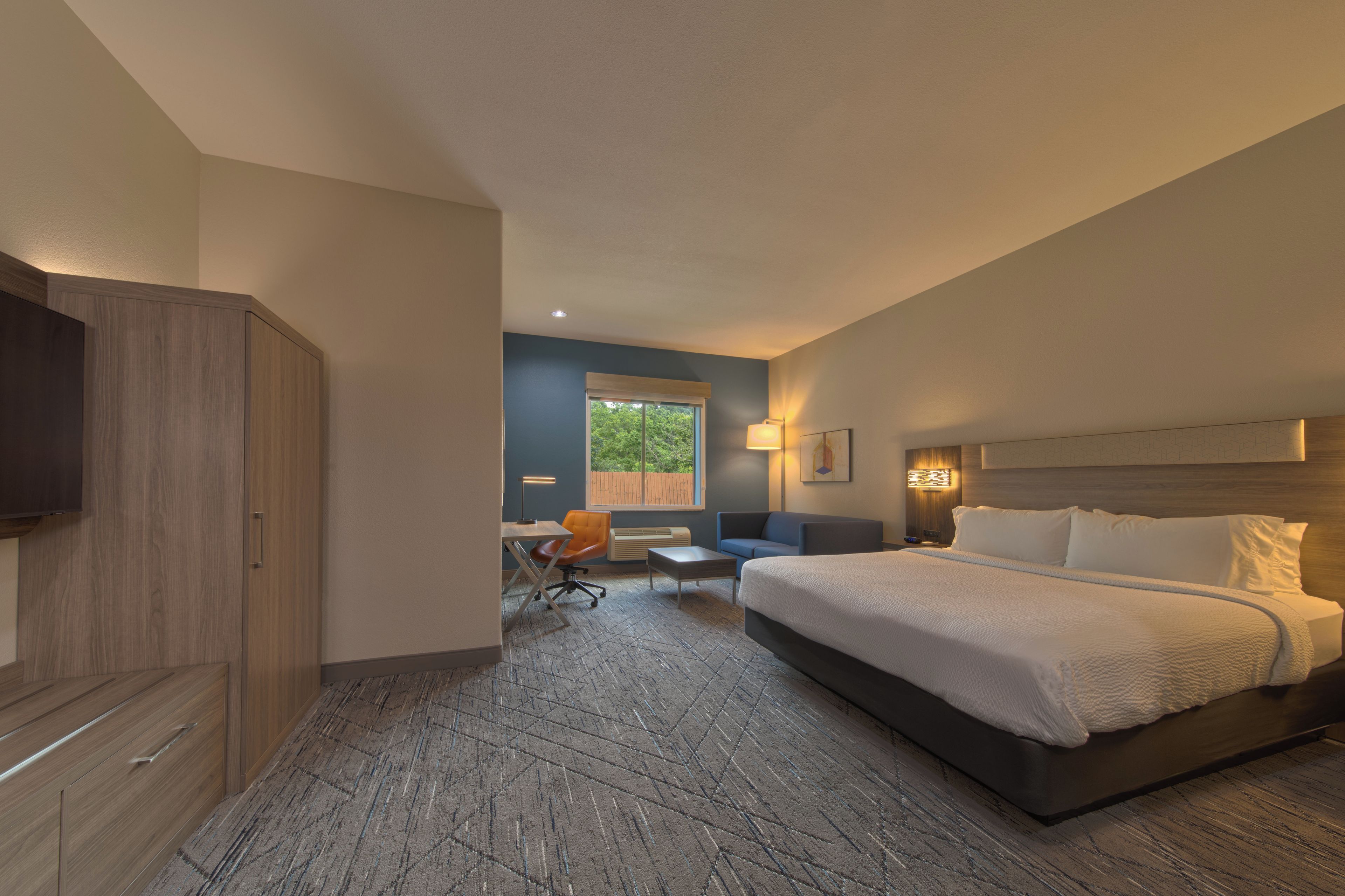 A hotel room with a bed, a desk, a chair, and a TV.