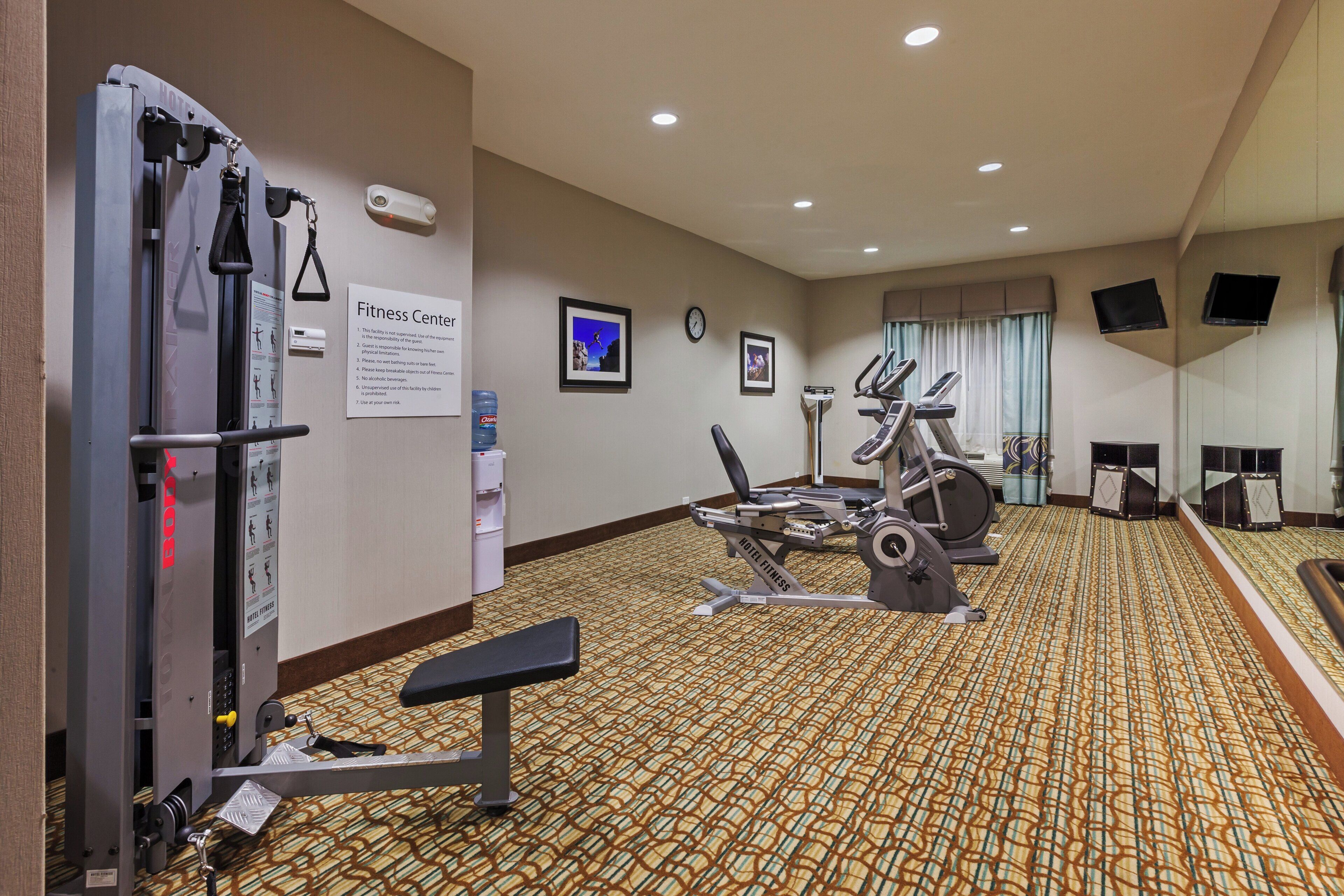A hotel fitness center with cardio machines, a weight bench, and a water dispenser.