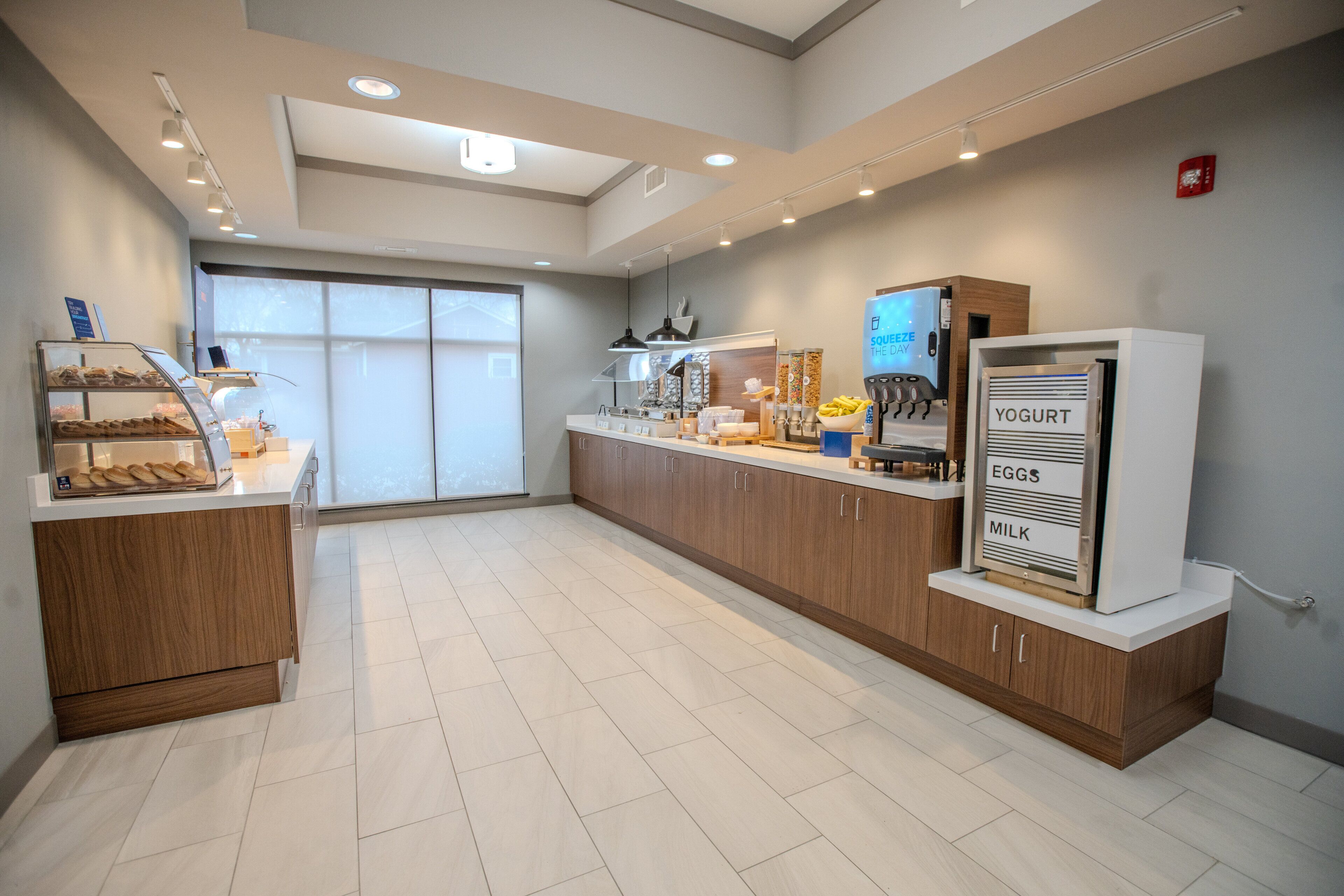 A modern kitchen with a built-in refrigerator, a display case with pastries, and a counter with a coffee machine.