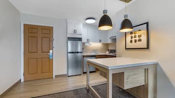 Uma cozinha moderna com armários brancos, eletrodomésticos de aço inoxidável e iluminação pendente.