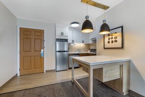 Une cuisine moderne avec des armoires blanches, des appareils en acier inoxydable et des luminaires suspendus.
